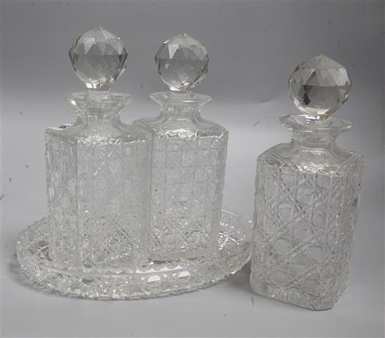 A set of three cut glass cased decanters and an oval cut glass bowl, tallest 23cm